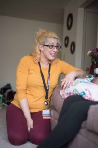 This is a photo of Yaisa Burgos sitting next to a couch and talking to a woman.