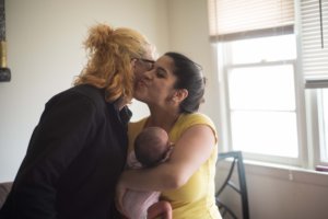 This is a photo of Yaisa Burgos and a woman greeting each other while the woman holds a baby.