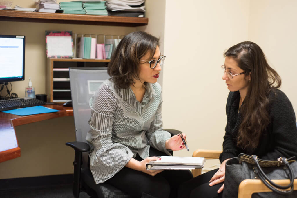 This is a photo of a community health worker helping a woman with paperwork. 