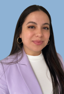 This is a headshot of Paulina Lopez. She is a Latina woman wearing a purple blazer and white shirt.